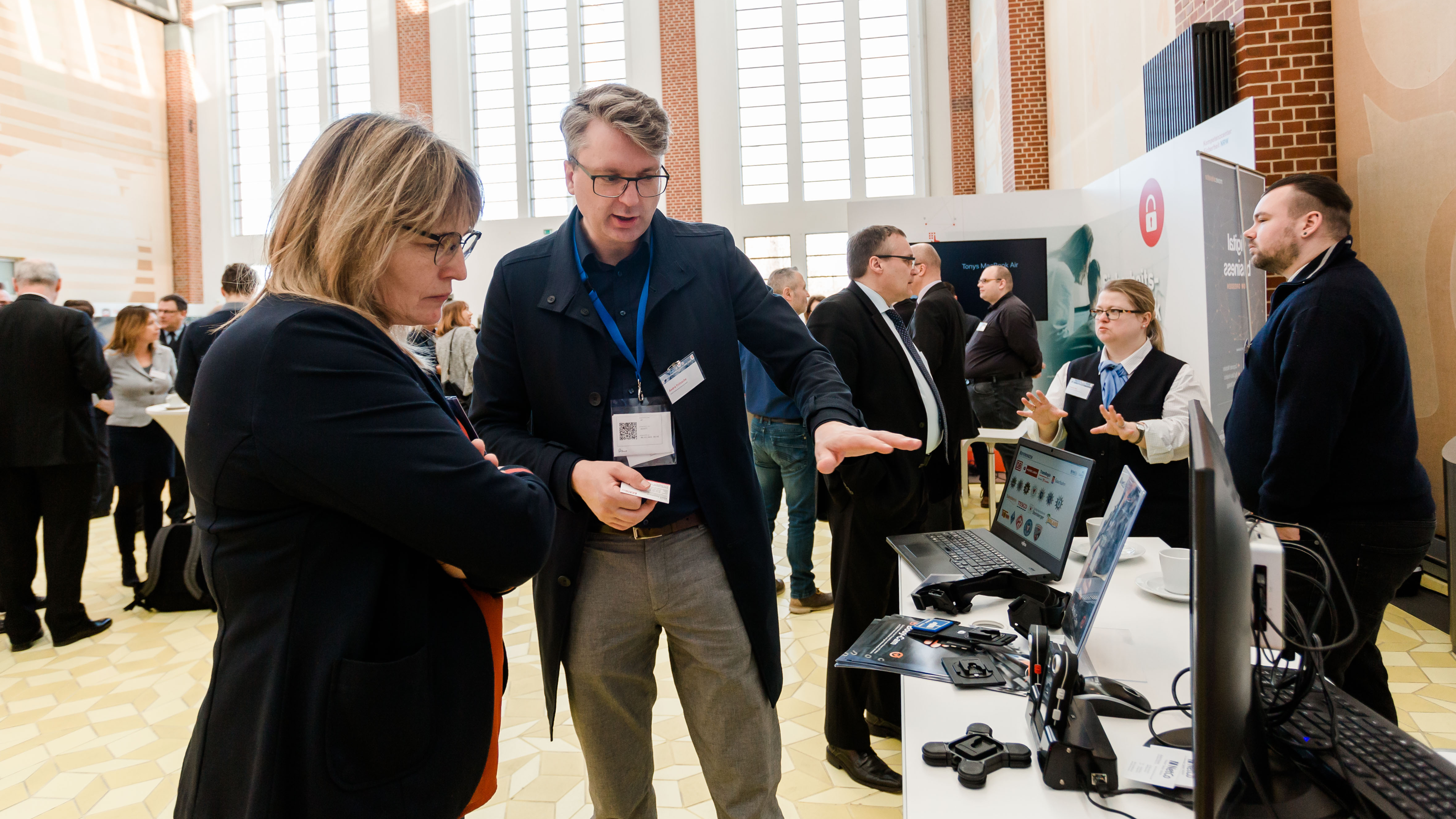 Ein Aussteller zeigt einer Frau mehrere Bodycams. - öffnet Bild in größerer Ansicht