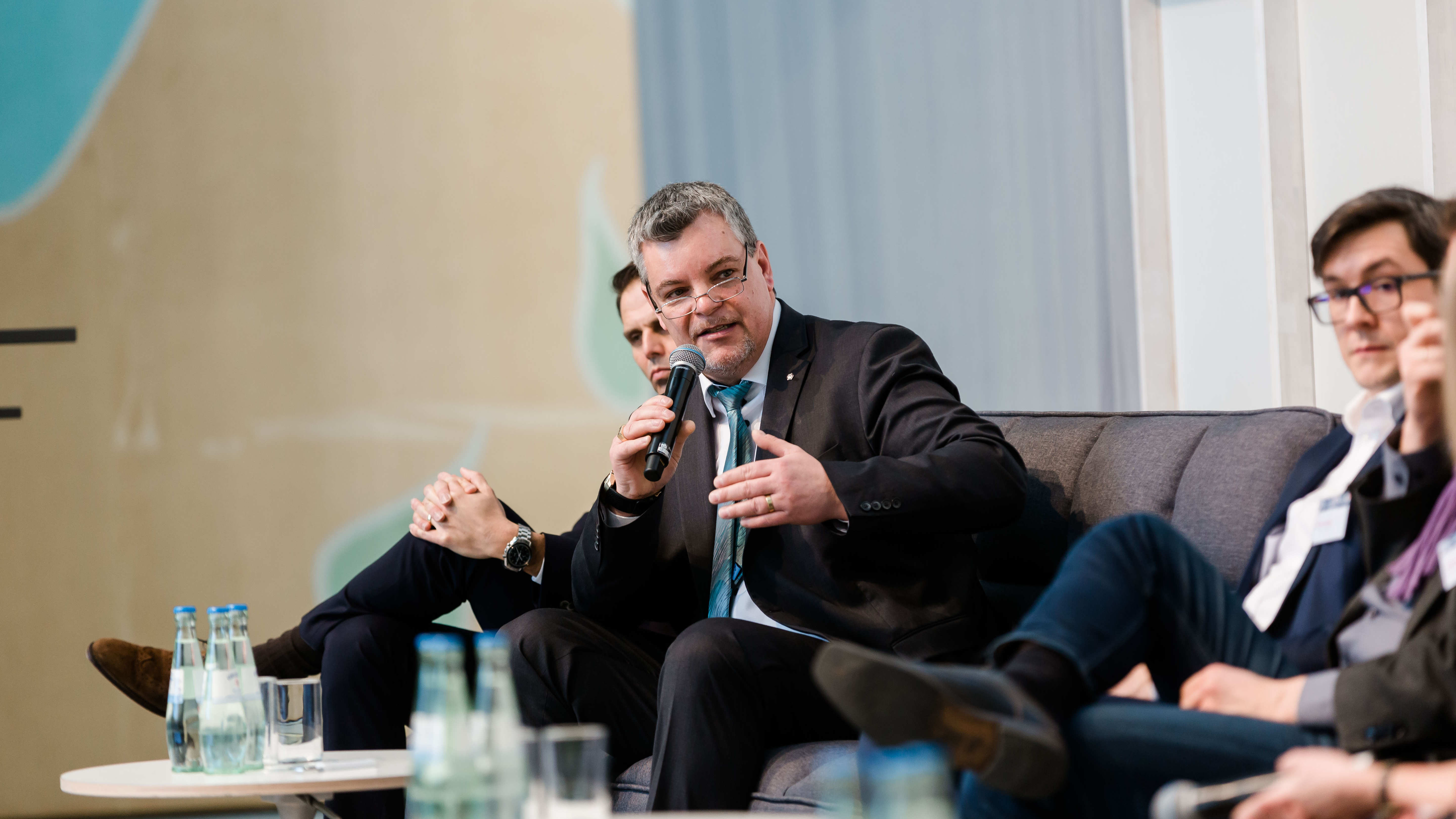 Teilnehmer einer Podiumsdiskussion reden miteinander auf der Bühne. - öffnet Bild in größerer Ansicht